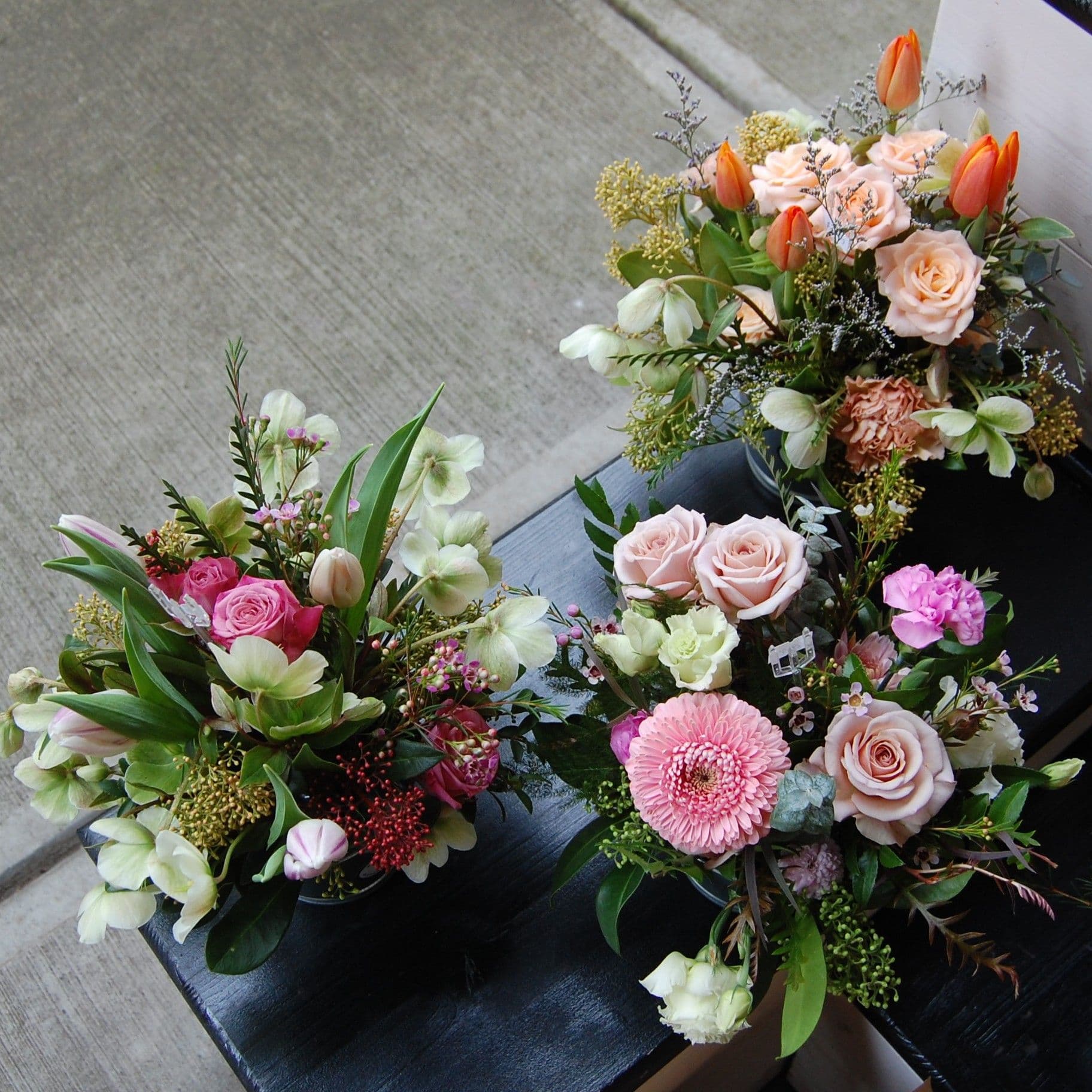 Top-down view of bouquets with roses, tulips and gerbera daisies on a bench