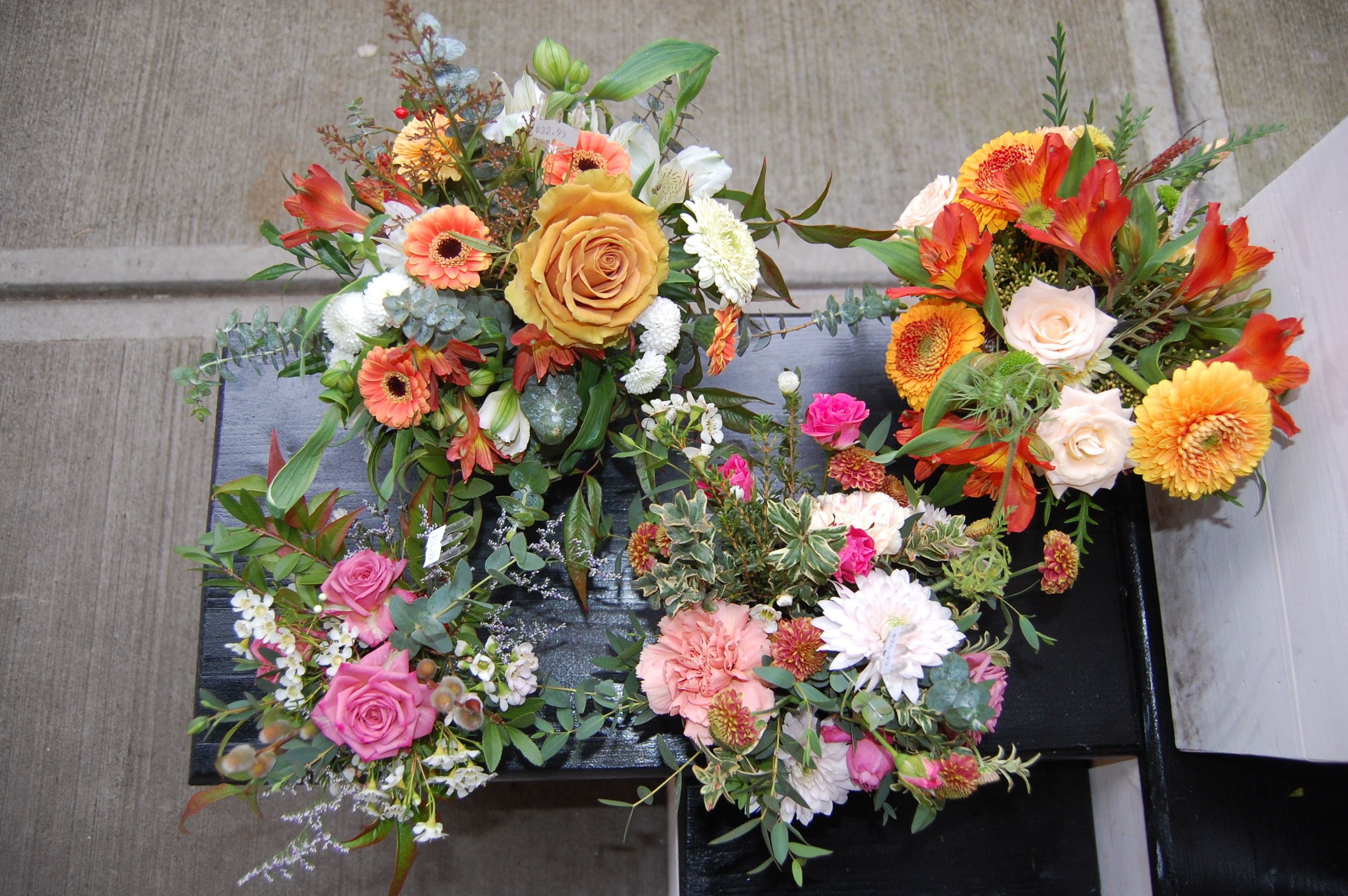 Framed Seaberry Garden & Flower logo above bouquets in tin pails with a sunset landscape painting